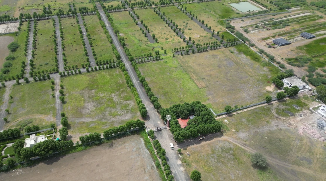 Actual aerial site view of the entrance, tree-lined roads and plots